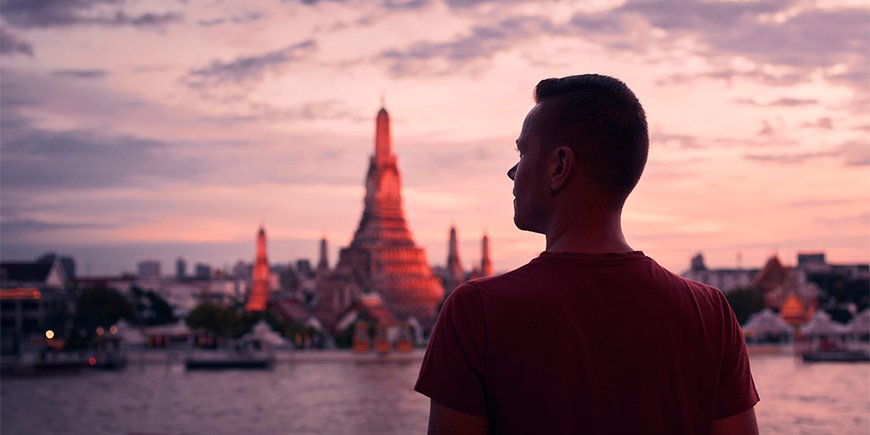 Mann står foran Wat Arun i Thailand ved solnedgang