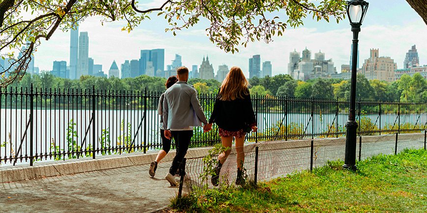 Et par går hånd i hånd i solskinn i Central Park i New York City